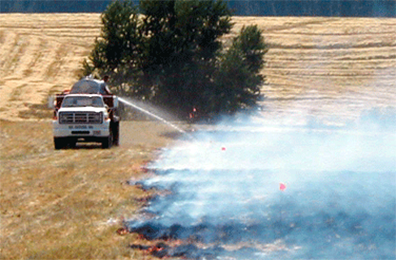 truck spraying water on burned field