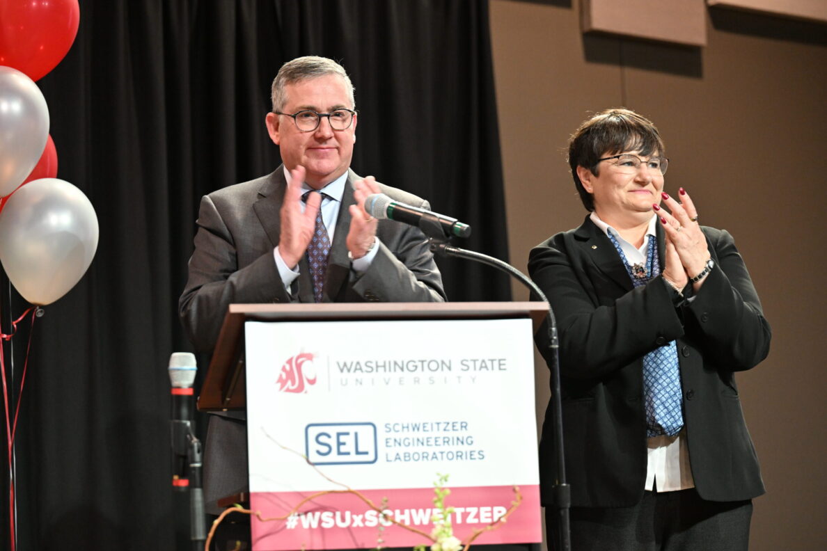 Kirk and Noel Schulz clapping at a podium that has the WSU and SEL logos and the text #WSUxSCHWEITZER.