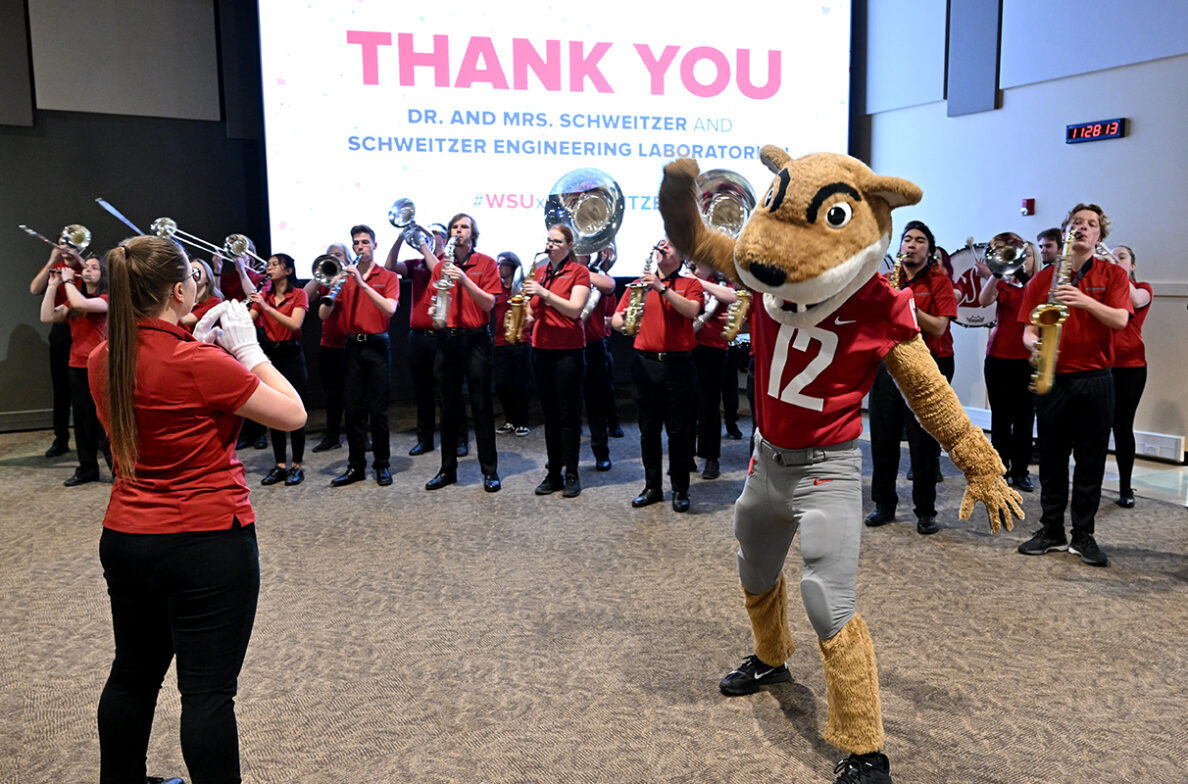 WSU band and Butch T. Cougar perform in front of a screen that reads Thank you Dr. and Mrs. Schweitzer and Schweitzer Engineering Laboratories.