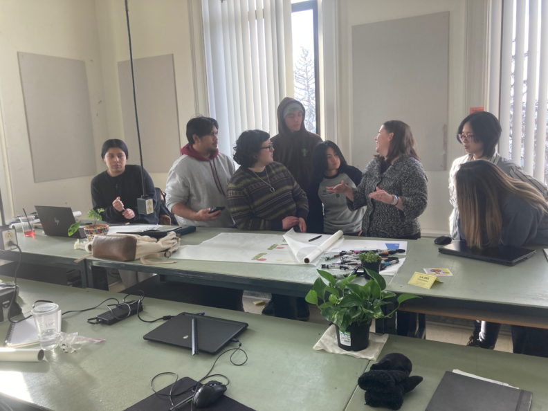 Students and professor gathered at a studio table.