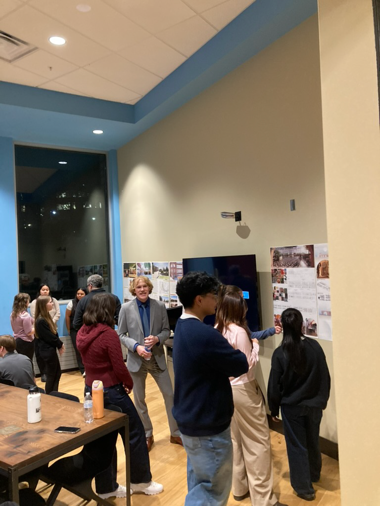 Group of students gathered in a gallery featuring their work.