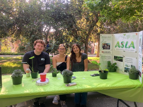 Three students seated at a table outside.