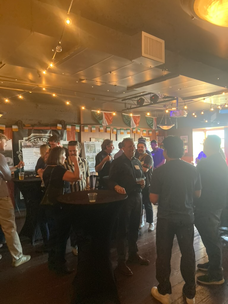 A small crowd of people in a venue having drinks and talking.