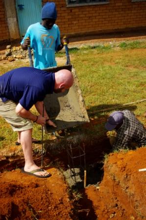 Men filling a trench with concrete.