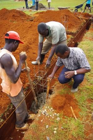 Three men prepare a building foundation.