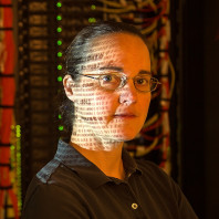 Jennifer Adam in the Information Technology Building Server room with data projected on her face.