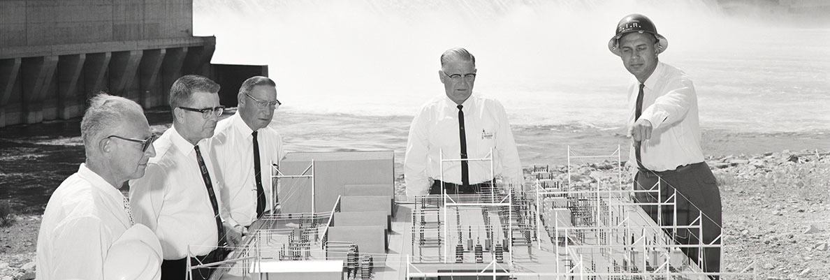 Historical image of men looking at a model of the Grand Coulee dam.