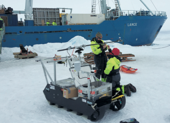 Two researchers working with equipment in the arctic.