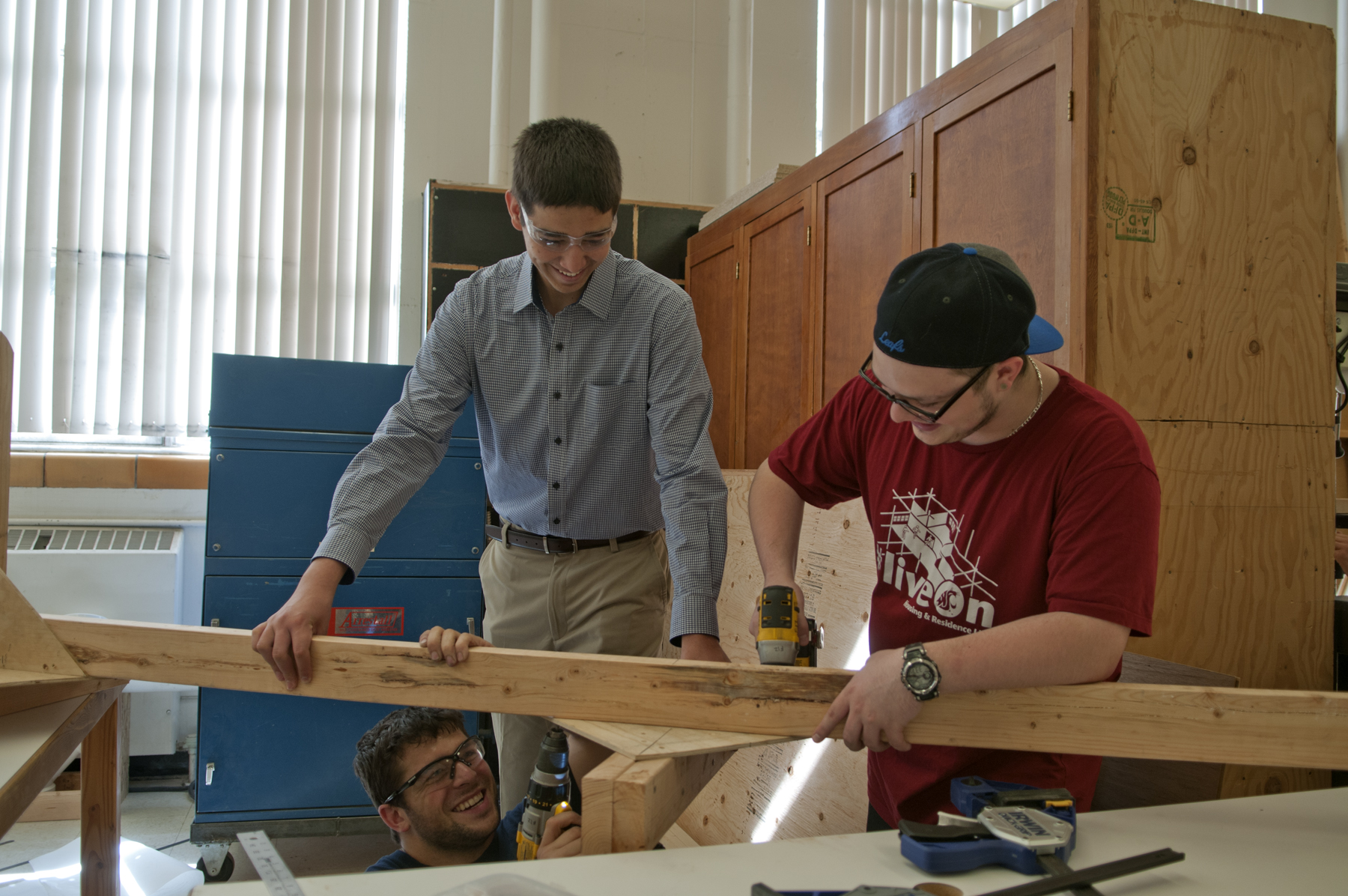 Three students working together to build a large wood frame.