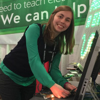 Kaitlyn Franz smiles for the camera while hooking up electrical equipment at the Digilent booth.