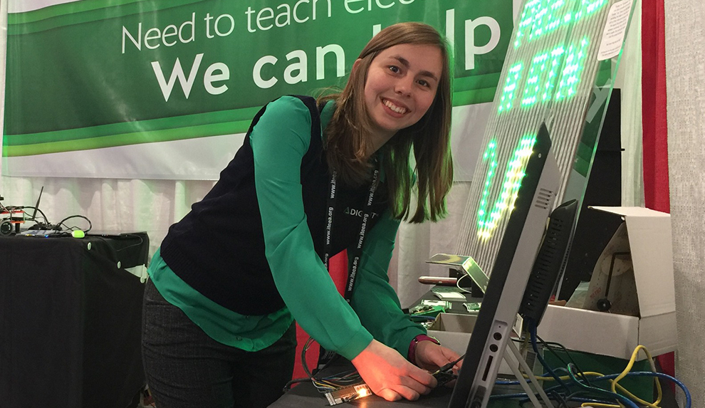 Kaitlyn Franz smiles for the camera while hooking up electrical equipment at the Digilent booth.