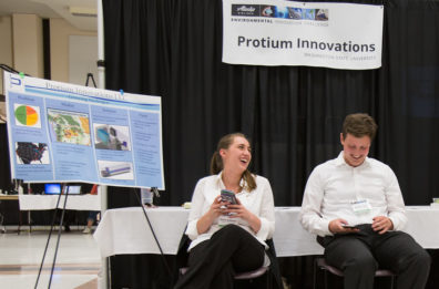 Bailee and Mitchell sit in chairs by their product booth.