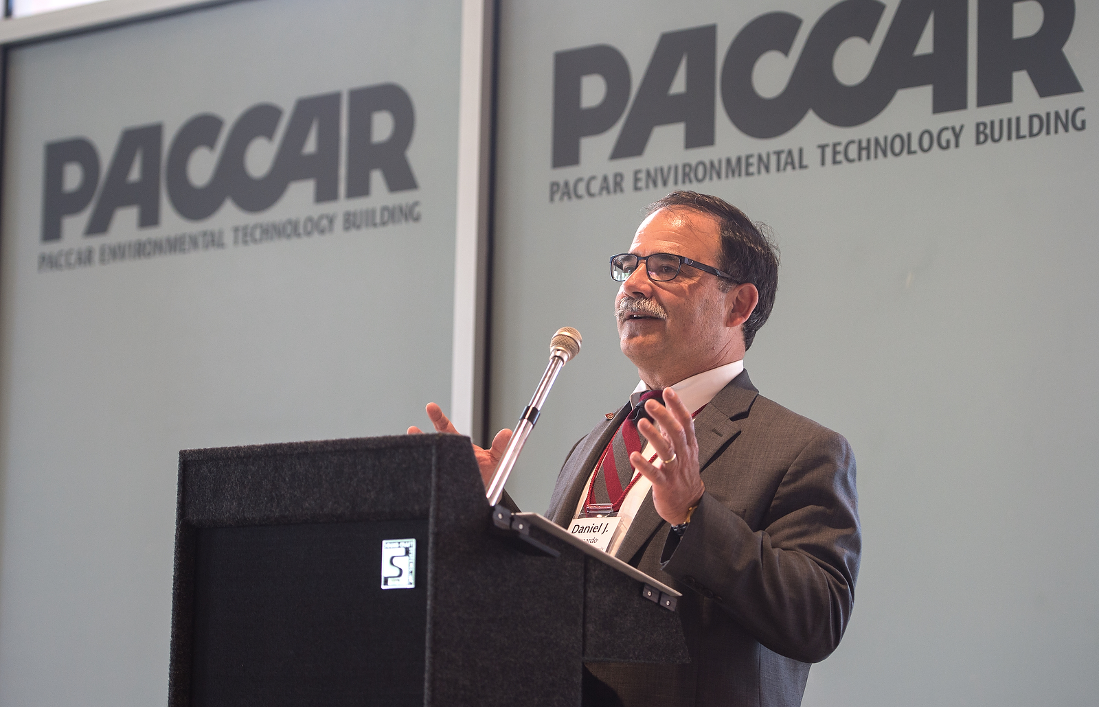 Dan Bernardo at a podium with a wall displaying "PACCAR Environmental Technology Building" behind him.
