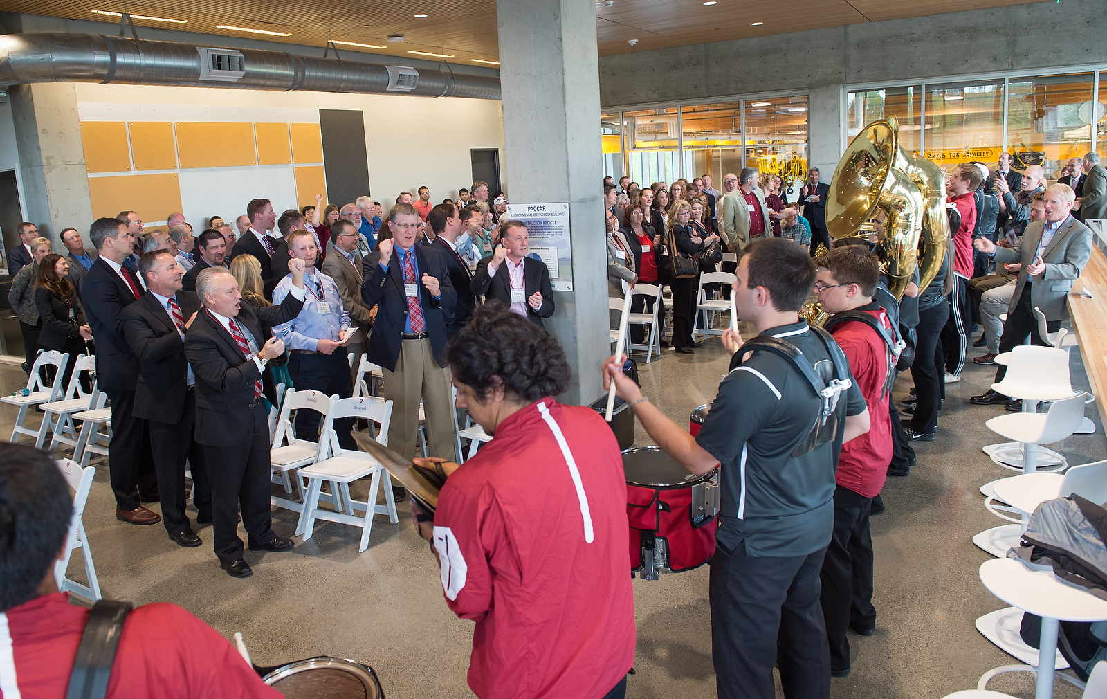 Dedication attendees stand and sing while the marching band performs.