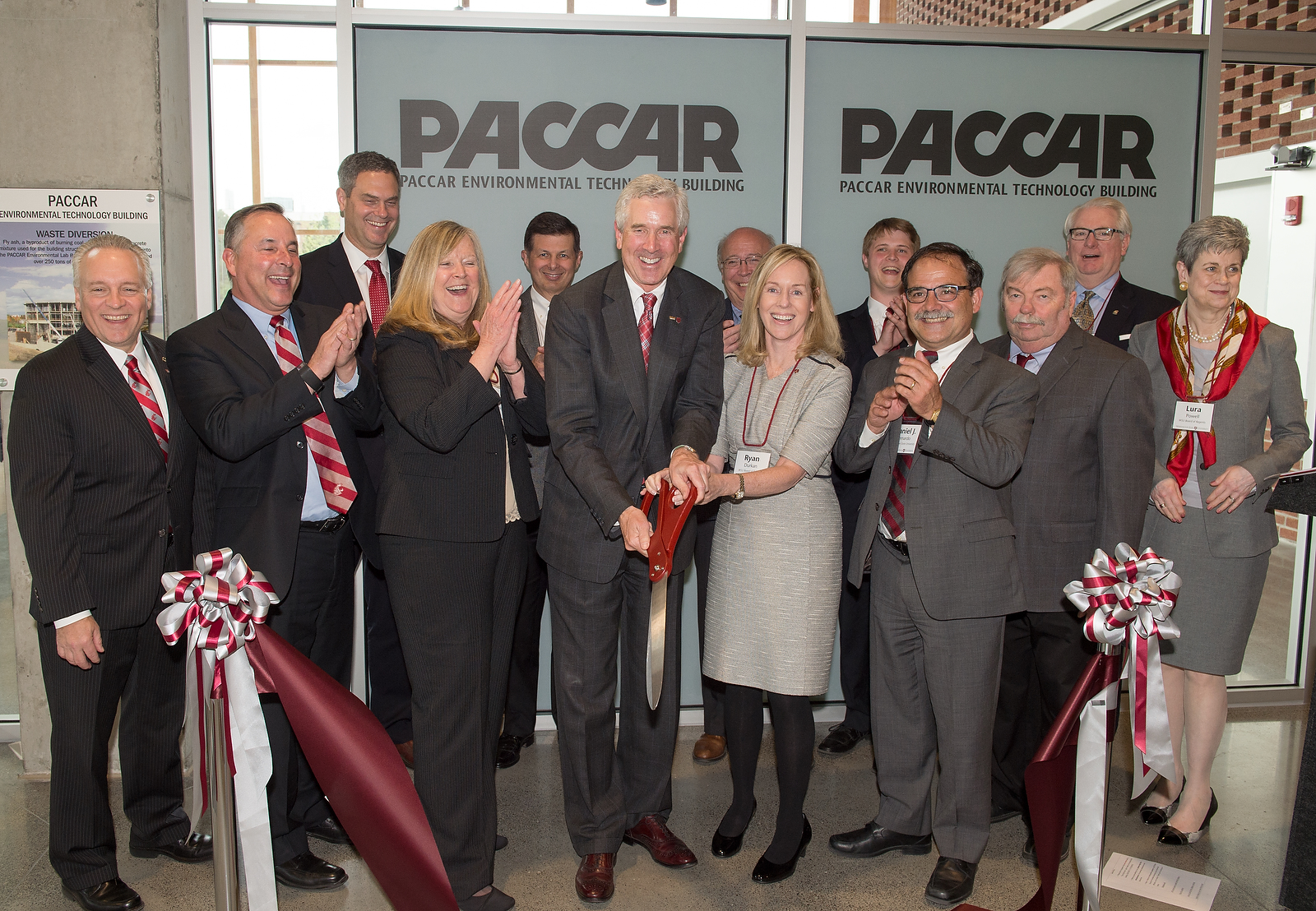 Stakeholders smiling and clapping upon cutting a ribbon for a building dedication.