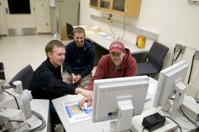 Dave Field and two students seated in front of computer screens.