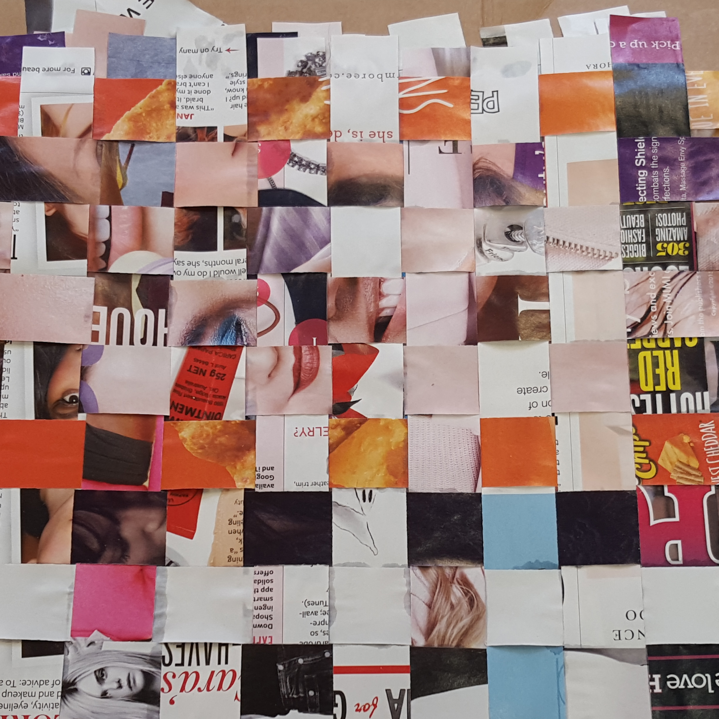 Strips cut from magazine pages are woven to create a wall.