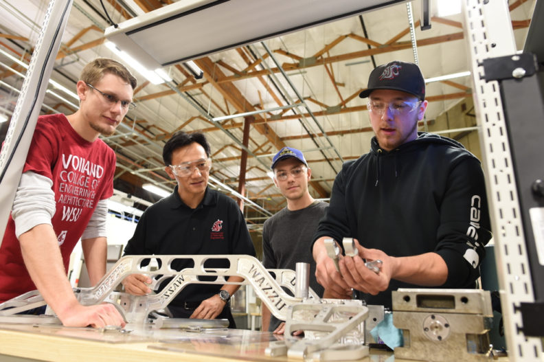 People inspecting components at a workbench.