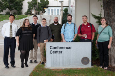 Xiaopeng Bi and students pose by a sign that reads Conference Center.