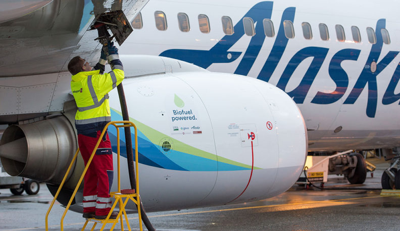 Jared Svraka stands on a step ladder to fuel an Alaska Airlines plane.