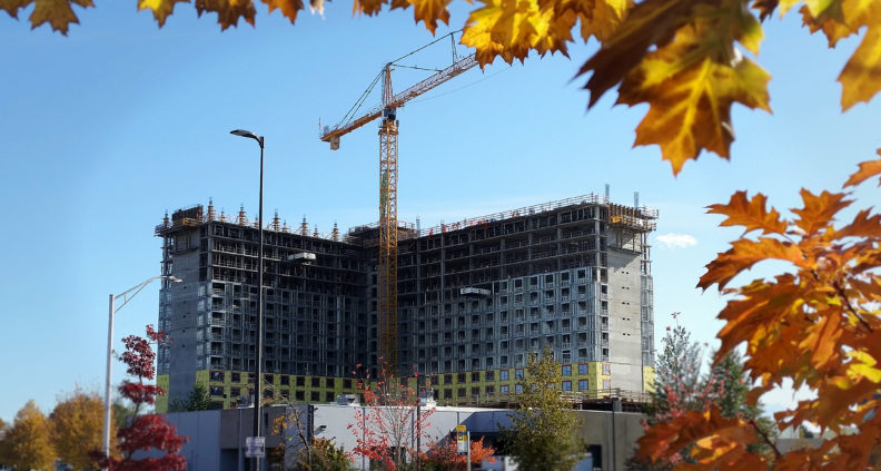 A large crane next to a multistory building that is under construction.