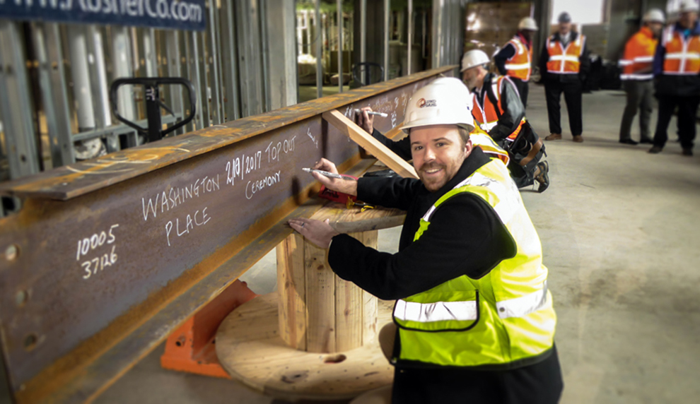 Bernt Johnson writes on a beam at the construction site of Washington Place.