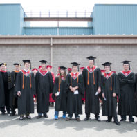 Graduates posing in a row wearing their caps and gowns.