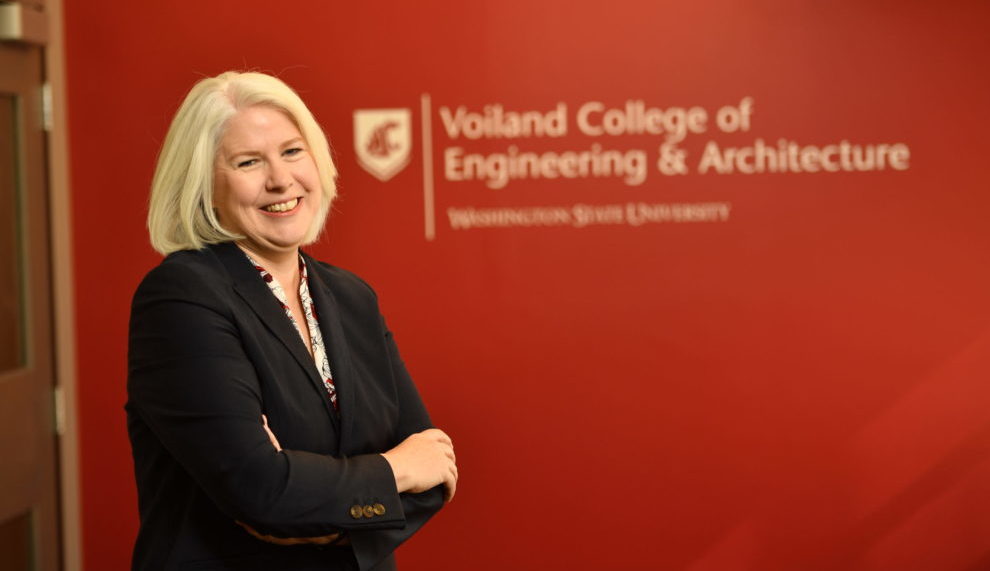 Dean Rezac stands in front of a crimson wall that has the Voiland College logo.