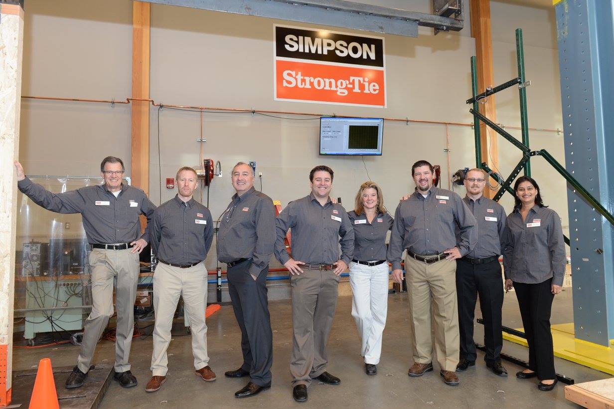 Men and women wearing grey-colored Simpson Strong-Tie t-shirts, posing for the camera.