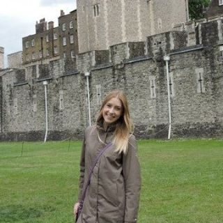 Roslyn VanSickle standing on a green lawn in front of a stone castle.