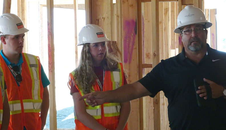 Abigail Shane, another student, and a construction professional wearing hard hats.