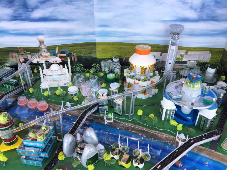 A model of a futuristic city with a river and bridges.