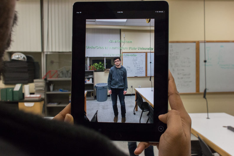Person is holding an iPad up with Kaveh in the camera being scanned by the app.
