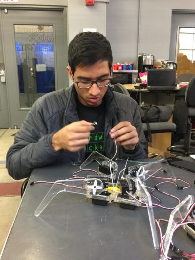 Student sitting at a table connecting wires.