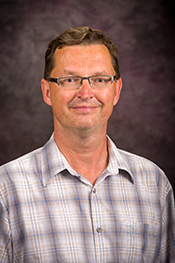 Peter Pfromm posing in a plaid, buttoned shirt.