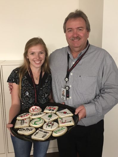 Mary and her father present a platter of decorated cookies.
