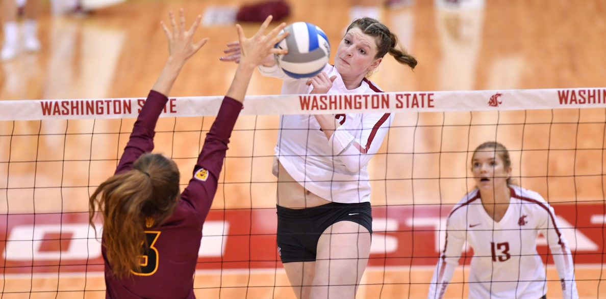 Claire Martin spikes the volleyball over the net as an opponent tries to block.
