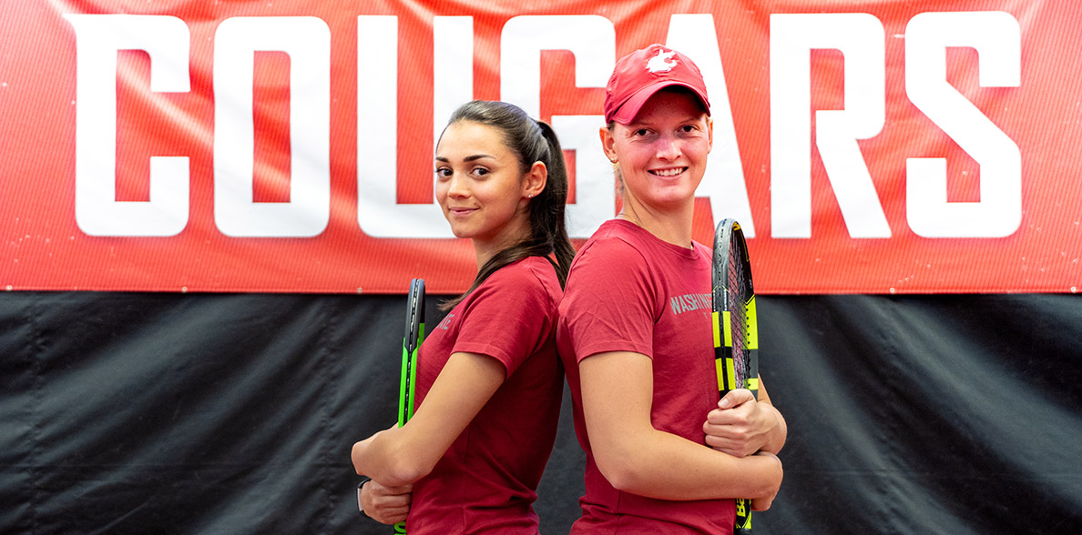 Gizem Melisa Ates and Michaela Bayerlova pose back to back on the tennis court.