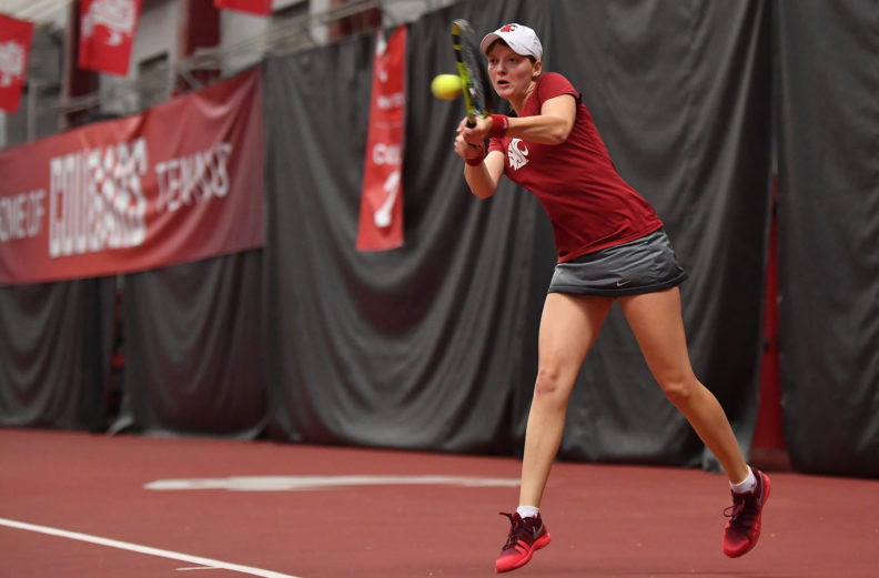 Michaela Bayerlova hits a ball on the tennis court.