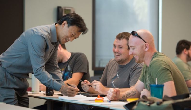 Xiaopeng Bi looking at a paper with two students.