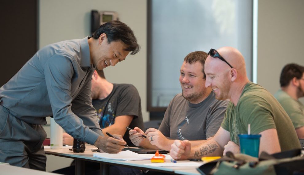 Xiaopeng Bi looking at a paper with two students.