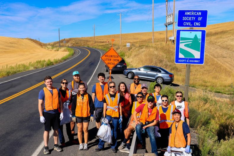 Madison Broers and the ASCE club pose in orange vests on the side of the highway while removing litter.