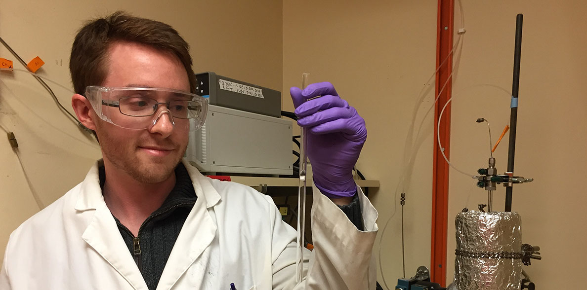 Jake Gray holds a catalyst up for the camera in a lab.