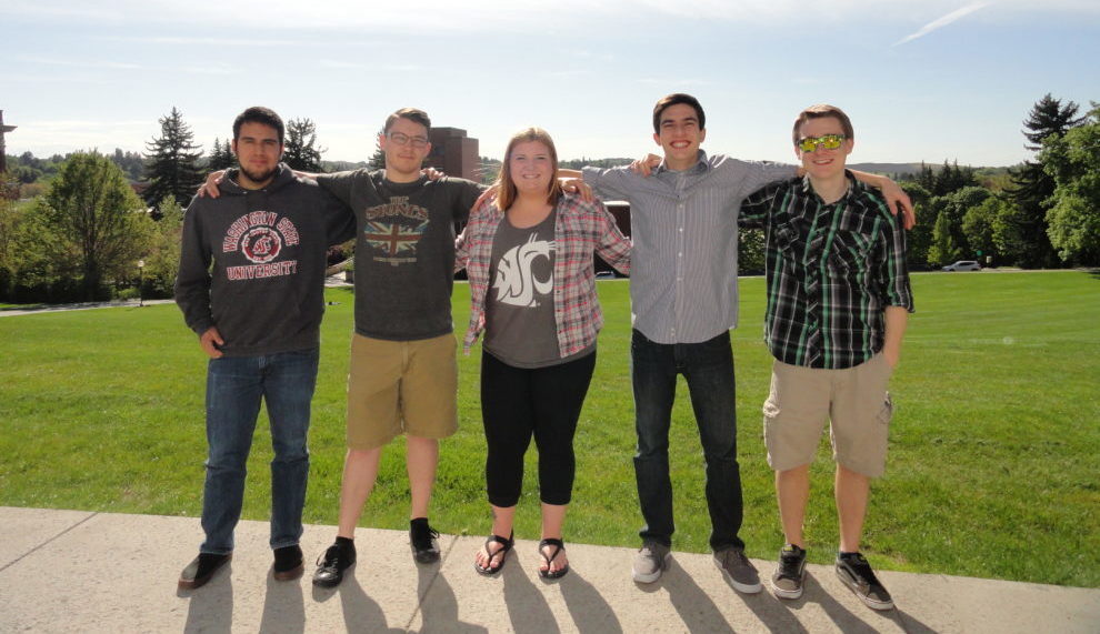 Five students standing in a row with their arms around each other's shoulders.