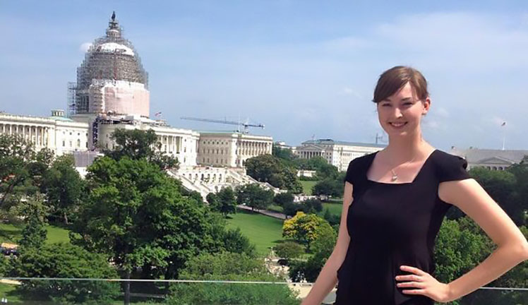 Alyssa Norris posing with United States Capitol under construction in the background.