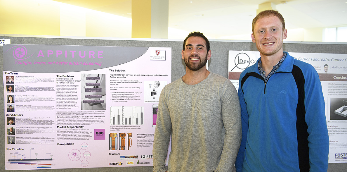 Lars Neuenschwander and TJ Goble standing beside a poster describing their autism-detection app.