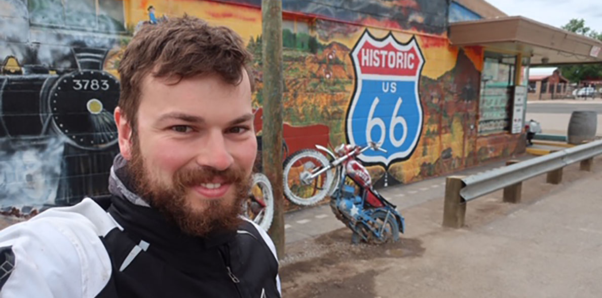 Florian Baertsch next to a Route 66 mural and motorcycle sculpture.