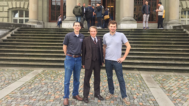 Three men standing in front of a building with steps and columns.