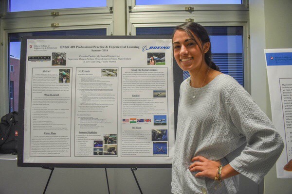 Christina poses next to a poster of her ENGR 489 presentation.
