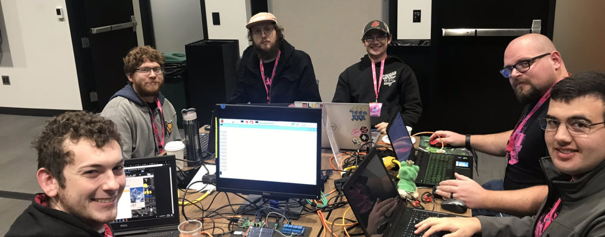 Six students using laptops sit around a table.